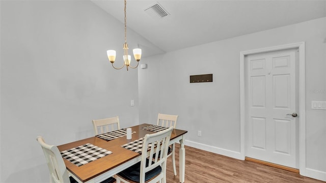 dining area with visible vents, baseboards, light wood-type flooring, lofted ceiling, and an inviting chandelier