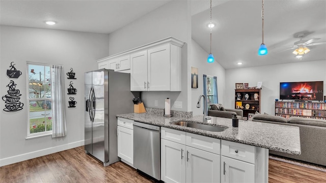 kitchen featuring open floor plan, stainless steel appliances, light wood-style floors, white cabinetry, and a sink