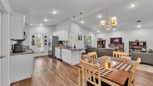 dining area featuring vaulted ceiling, visible vents, a notable chandelier, and wood finished floors