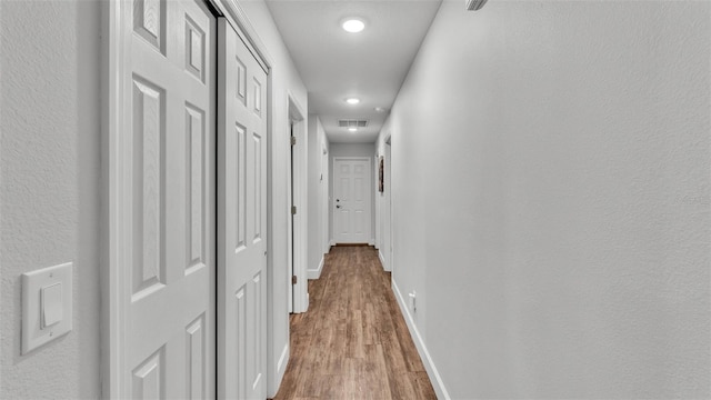 corridor featuring visible vents, baseboards, and light wood-style floors