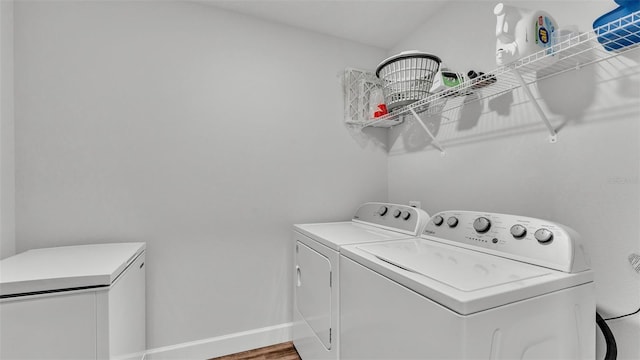 laundry room with laundry area, wood finished floors, baseboards, and washing machine and clothes dryer