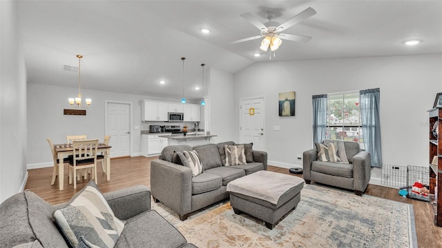 living room with visible vents, baseboards, lofted ceiling, light wood-style floors, and ceiling fan with notable chandelier