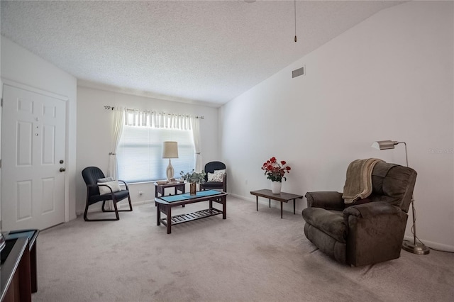 living area featuring lofted ceiling, light colored carpet, and a textured ceiling