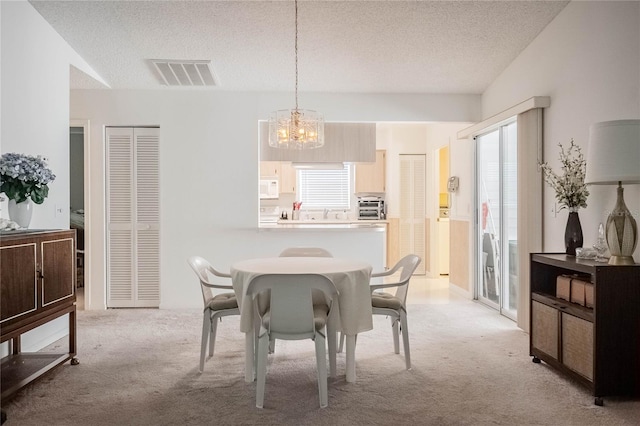 carpeted dining area with a chandelier and a textured ceiling