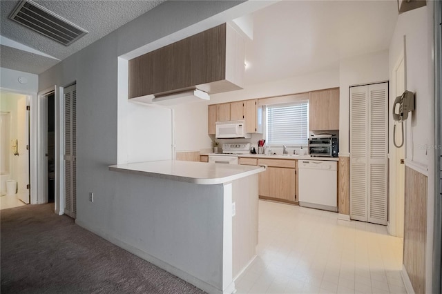 kitchen featuring sink, white appliances, kitchen peninsula, and a textured ceiling