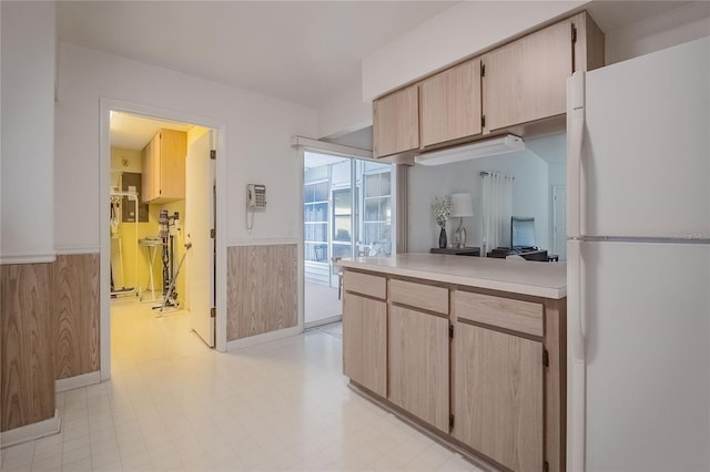 kitchen with light brown cabinets, wood walls, and white refrigerator