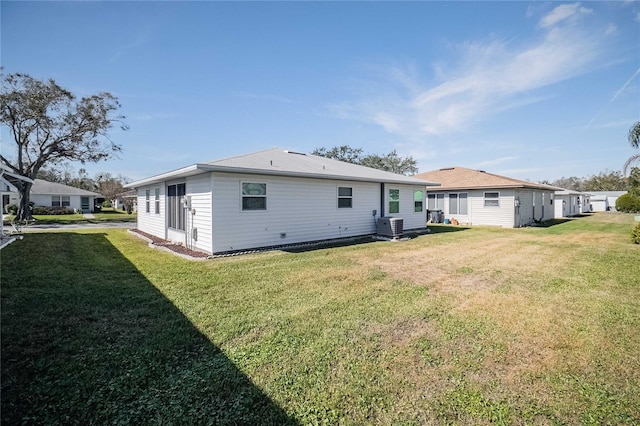 back of house with central AC and a lawn