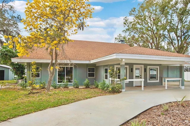 ranch-style home featuring a shingled roof, a porch, and stucco siding