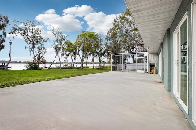 view of patio / terrace featuring glass enclosure and a water view