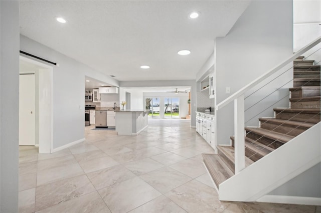 entryway with a barn door, stairway, a ceiling fan, and recessed lighting