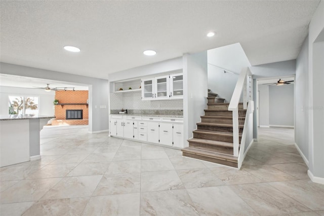 interior space featuring a textured ceiling, ceiling fan, a fireplace, and baseboards