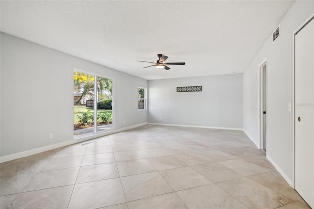 spare room featuring ceiling fan, light tile patterned floors, a textured ceiling, visible vents, and baseboards