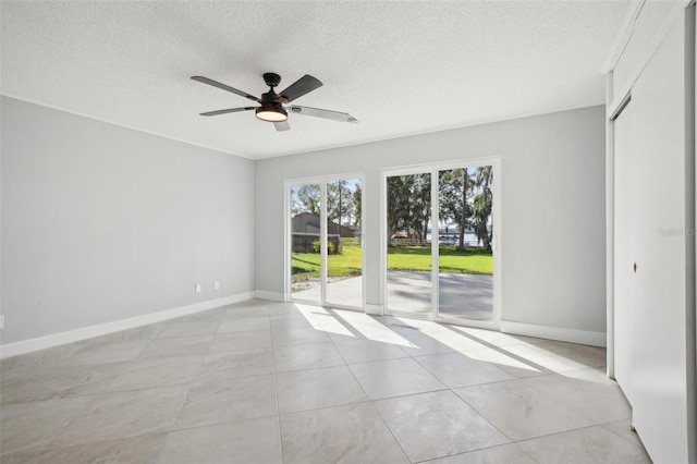 empty room featuring a textured ceiling, baseboards, and a ceiling fan