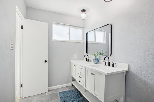 full bathroom with double vanity, a sink, baseboards, and tile patterned floors