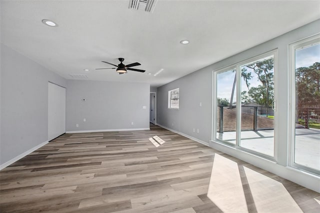 unfurnished room with baseboards, light wood-style floors, visible vents, and a healthy amount of sunlight