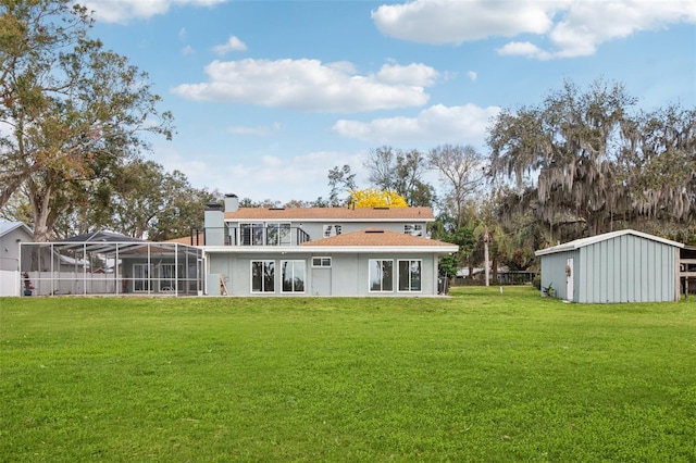 back of house featuring a lanai, a chimney, a lawn, and an outbuilding