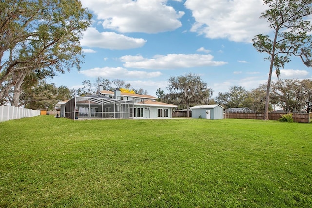 view of yard featuring a storage unit, an outdoor structure, a fenced backyard, and a lanai