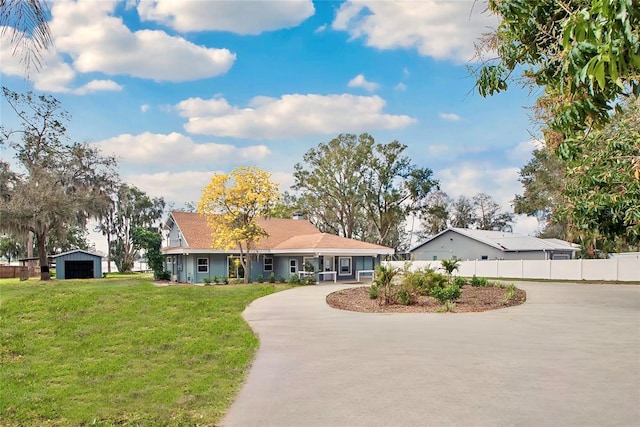 single story home featuring driveway, a garage, fence, an outdoor structure, and a front lawn