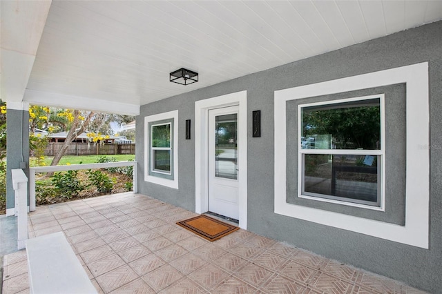 entrance to property featuring a porch and stucco siding