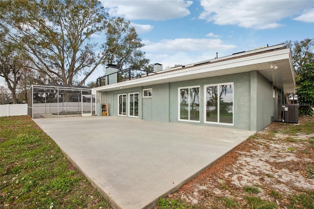 rear view of house featuring stucco siding, a patio, fence, and central air condition unit