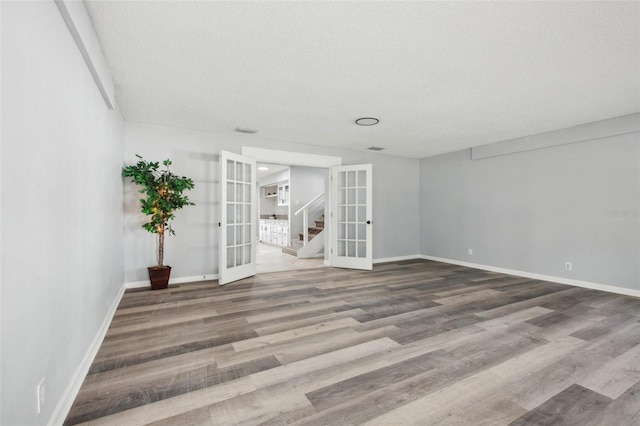 unfurnished room featuring a textured ceiling, wood finished floors, visible vents, baseboards, and french doors