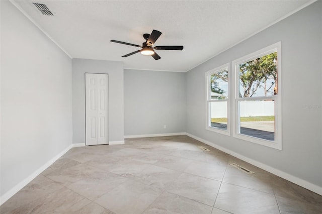 unfurnished room with a ceiling fan, visible vents, a textured ceiling, and baseboards