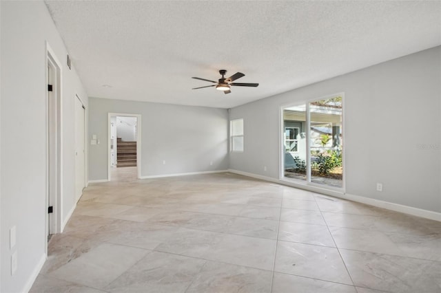 empty room featuring ceiling fan, baseboards, and a textured ceiling