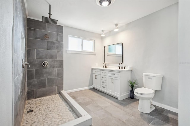 bathroom featuring toilet, double vanity, baseboards, and walk in shower