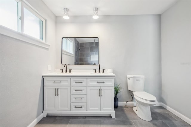 bathroom featuring baseboards, a sink, toilet, and tiled shower