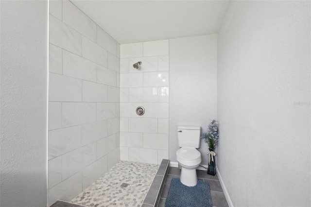 full bathroom featuring toilet, tile patterned flooring, and tiled shower