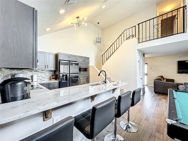 kitchen featuring gray cabinetry, tasteful backsplash, a textured ceiling, appliances with stainless steel finishes, and kitchen peninsula