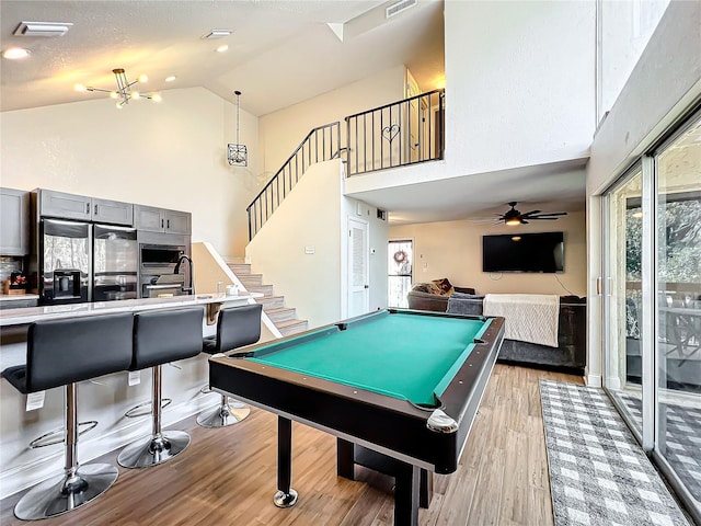 game room featuring high vaulted ceiling, billiards, a textured ceiling, and light wood-type flooring