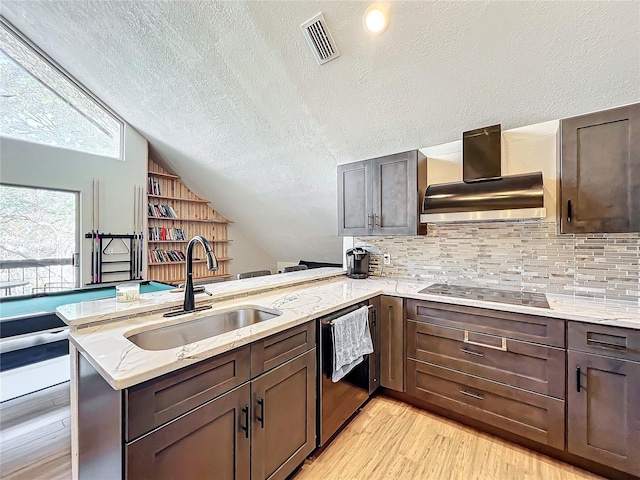 kitchen with black electric stovetop, kitchen peninsula, sink, and wall chimney range hood