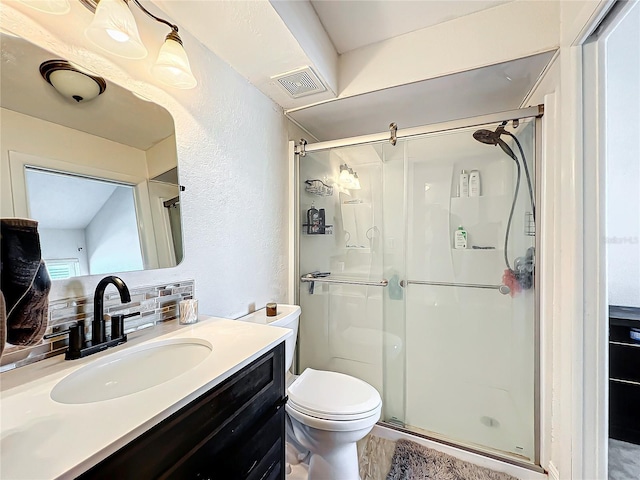 bathroom with vanity, decorative backsplash, a shower with door, and toilet