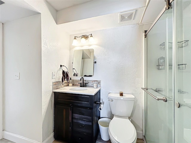 bathroom featuring vanity, backsplash, toilet, and walk in shower