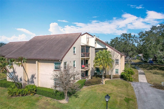 view of front of house with a front lawn and a balcony