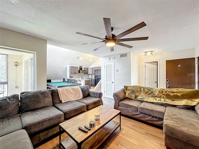 living room featuring lofted ceiling, light hardwood / wood-style flooring, billiards, ceiling fan, and a textured ceiling