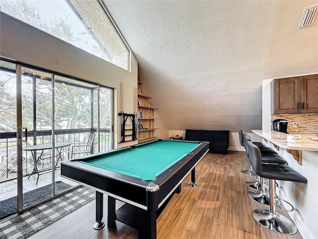 game room with lofted ceiling, billiards, a textured ceiling, and light hardwood / wood-style flooring