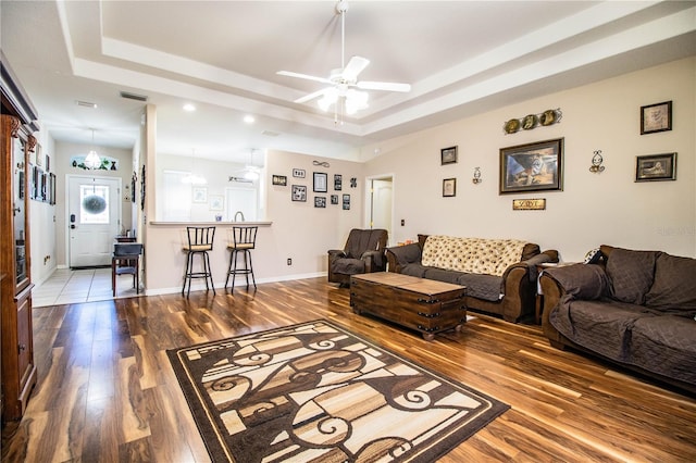 living room with hardwood / wood-style floors, ceiling fan, and a tray ceiling