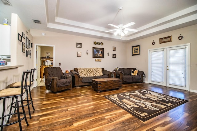 living room with french doors, ceiling fan, wood-type flooring, and a tray ceiling