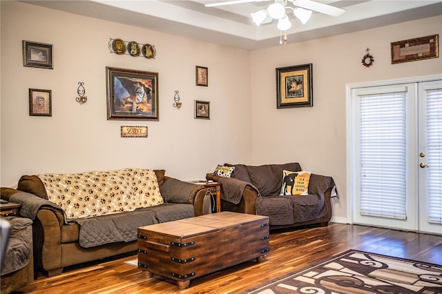 living room with a tray ceiling, hardwood / wood-style floors, ceiling fan, and french doors