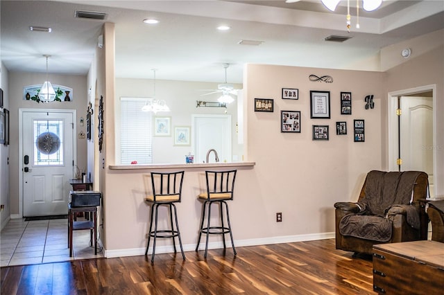 kitchen featuring dark wood-type flooring, ceiling fan, a kitchen breakfast bar, and hanging light fixtures