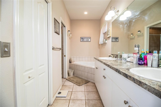 bathroom with tile patterned flooring, vanity, and tiled bath