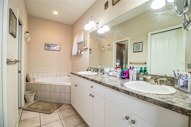 bathroom featuring vanity, tile patterned flooring, and tiled tub