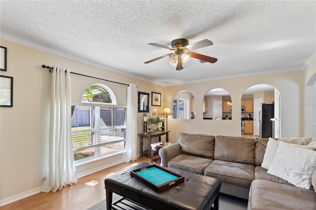 living room with a textured ceiling, crown molding, ceiling fan, and wood-type flooring