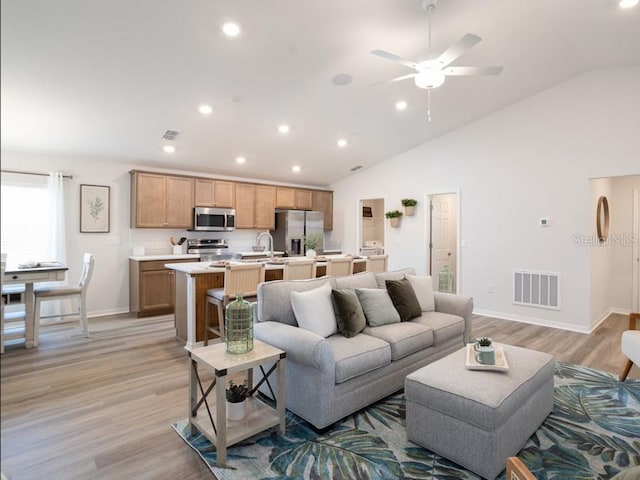 living room with sink, light hardwood / wood-style flooring, ceiling fan, and vaulted ceiling