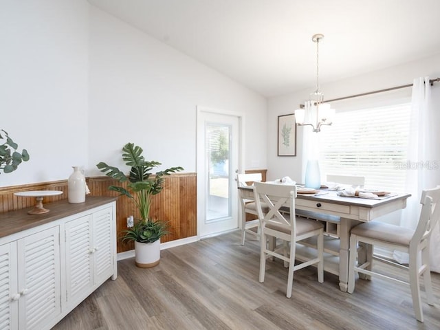 dining space featuring lofted ceiling, wood-type flooring, and a chandelier