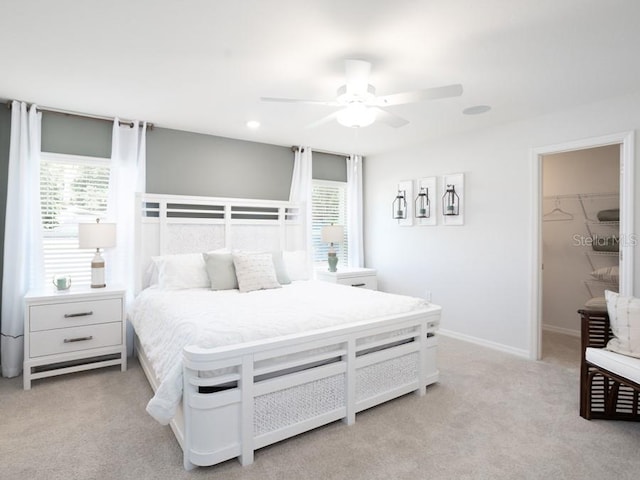 carpeted bedroom with multiple windows, a walk in closet, a closet, and ceiling fan