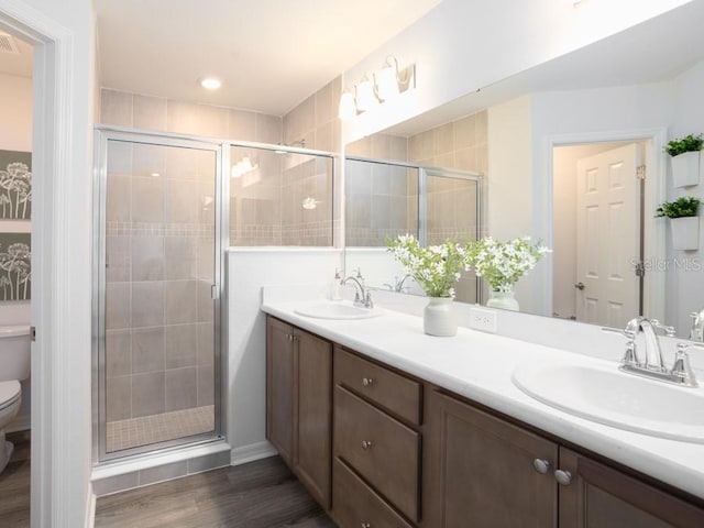 bathroom with wood-type flooring, toilet, a shower with door, and vanity