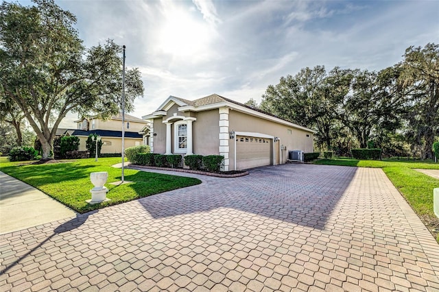 single story home featuring a garage, cooling unit, and a front lawn